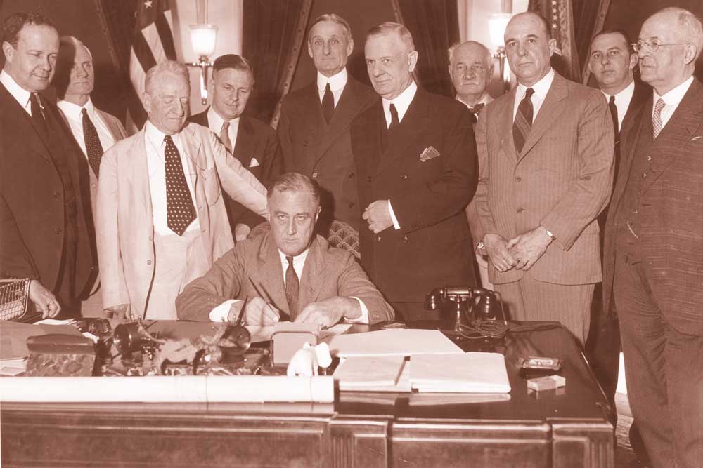 On June 16, 1933, President Franklin Roosevelt signed the Banking Act of 1933, a part of which established the FDIC, as a result of the stock market crash and Great Depression. This system provided insurance for each bank and their deposit accounts. At Roosevelt's immediate right and left were Sen. Carter Glass of Virginia and Rep. Henry Steagall of Alabama, the two most prominent figures in the bill's development.